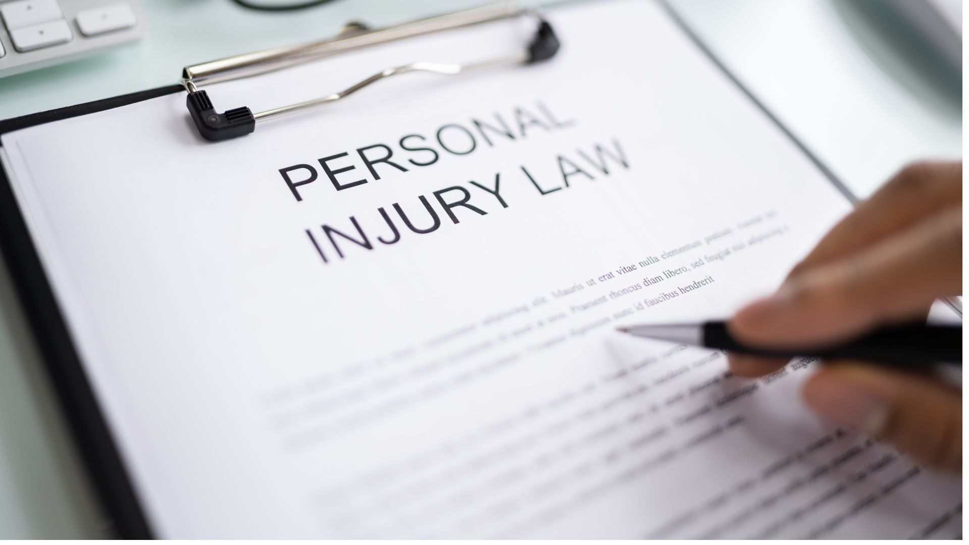 A person is signing a personal injury law document on a clipboard.