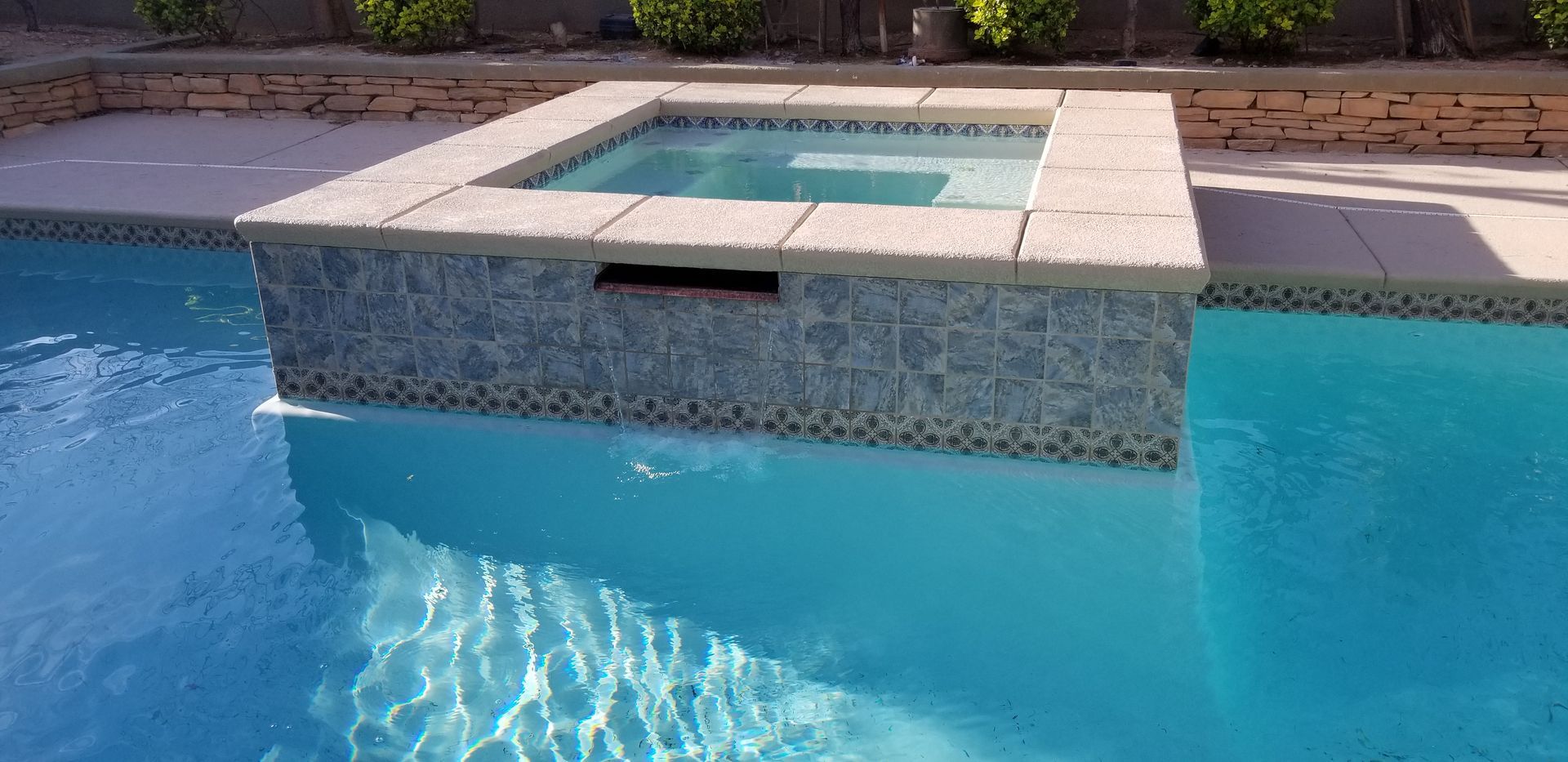 A swimming pool with a hot tub in the middle of it.