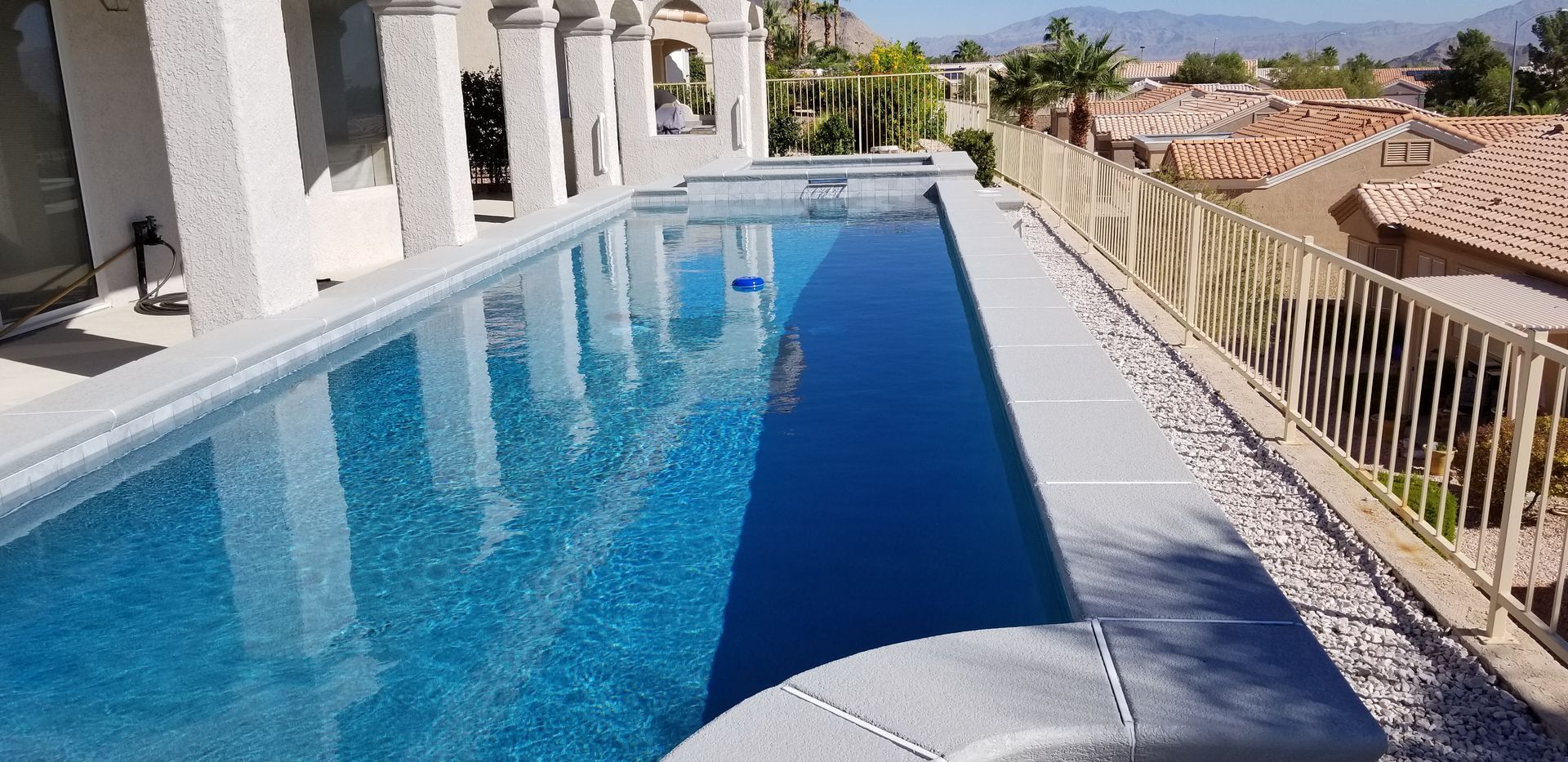 There is a large swimming pool in the backyard of a house.