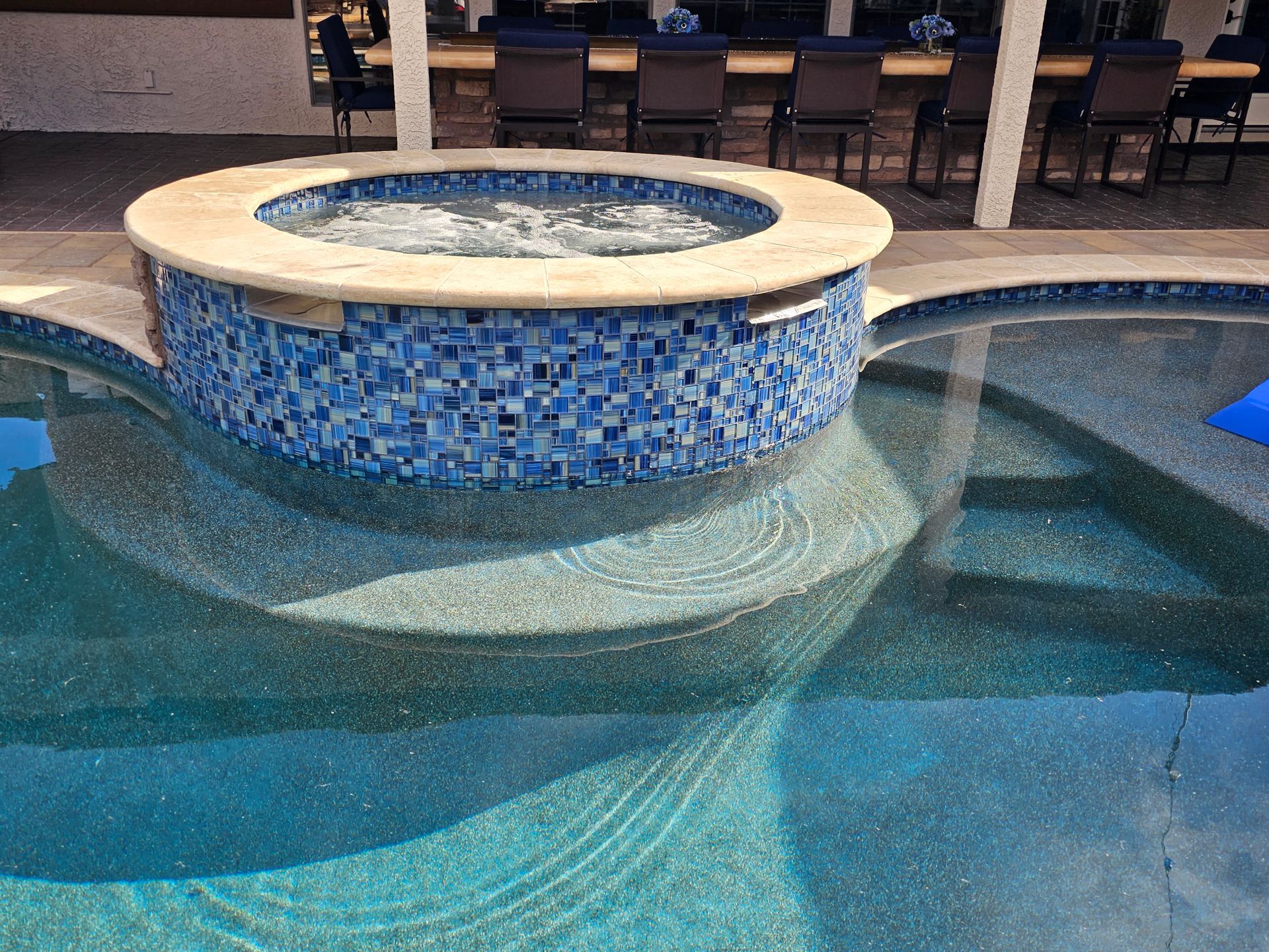 A swimming pool with a hot tub in the middle of it.