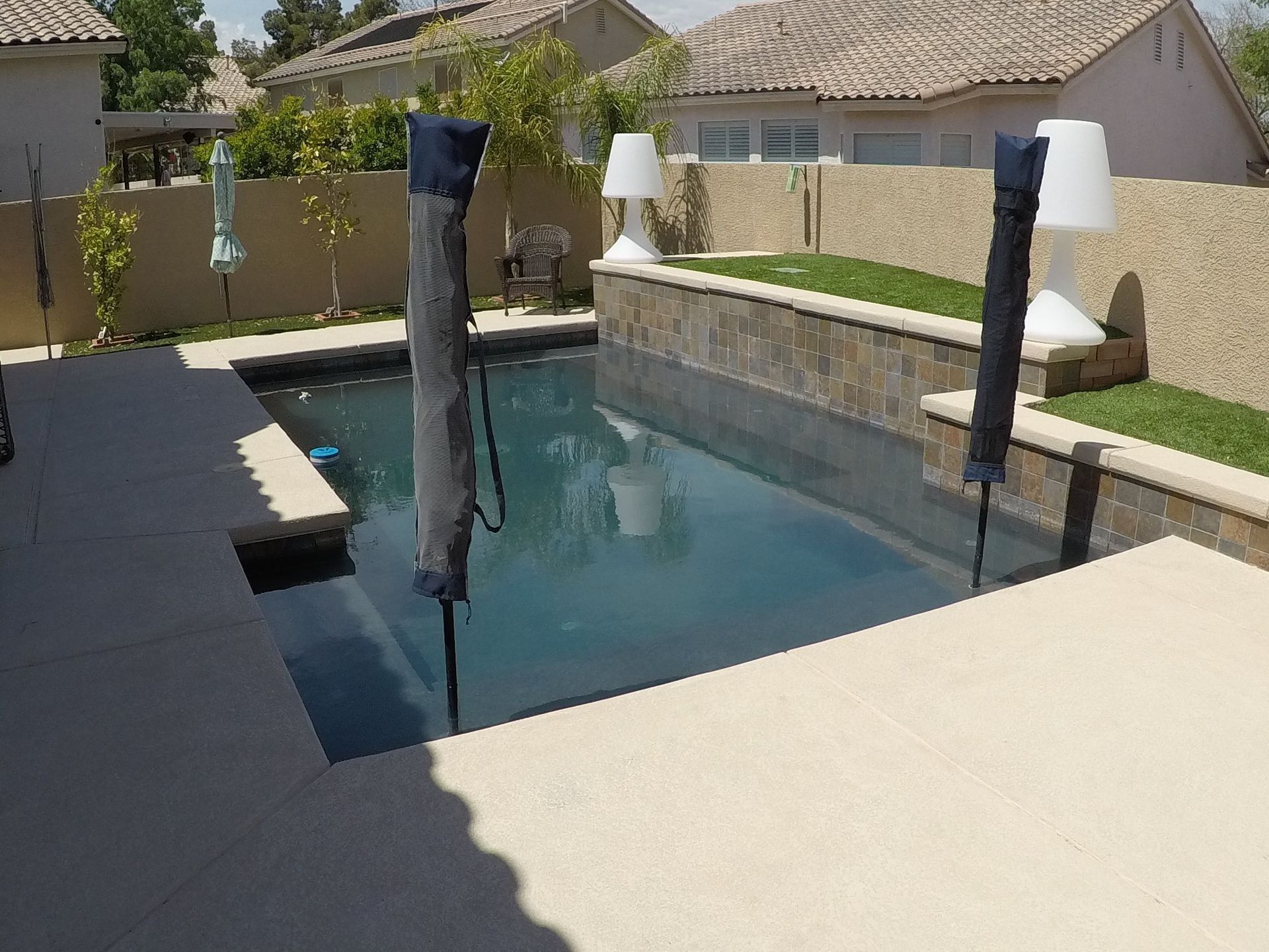A large swimming pool is surrounded by a fence and lamps