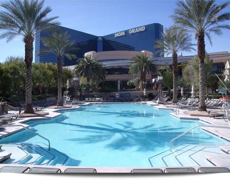 A large swimming pool in front of a mgm grand hotel