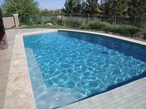 A large swimming pool filled with blue water in a backyard.