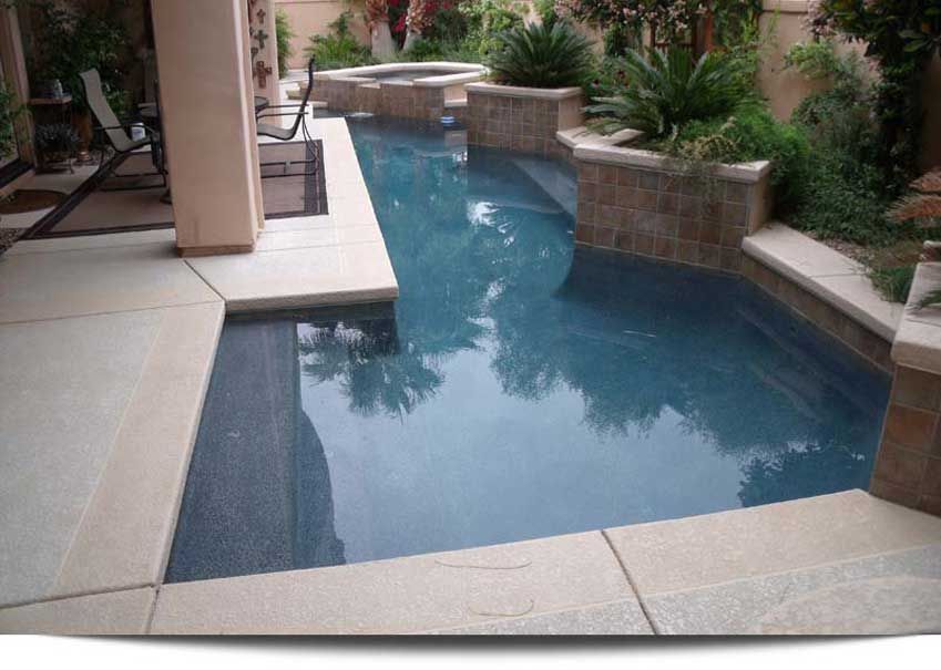 A large swimming pool with a hot tub in the backyard