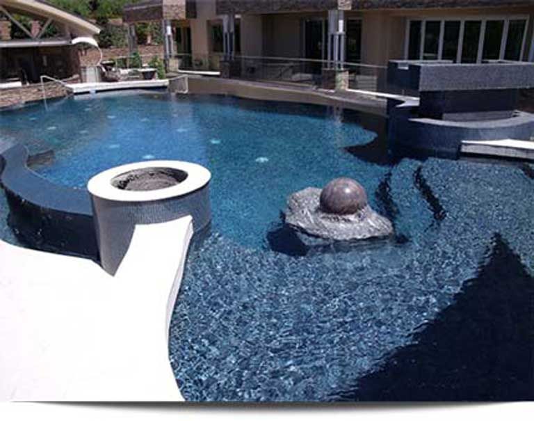 A large swimming pool with a fire pit in the middle