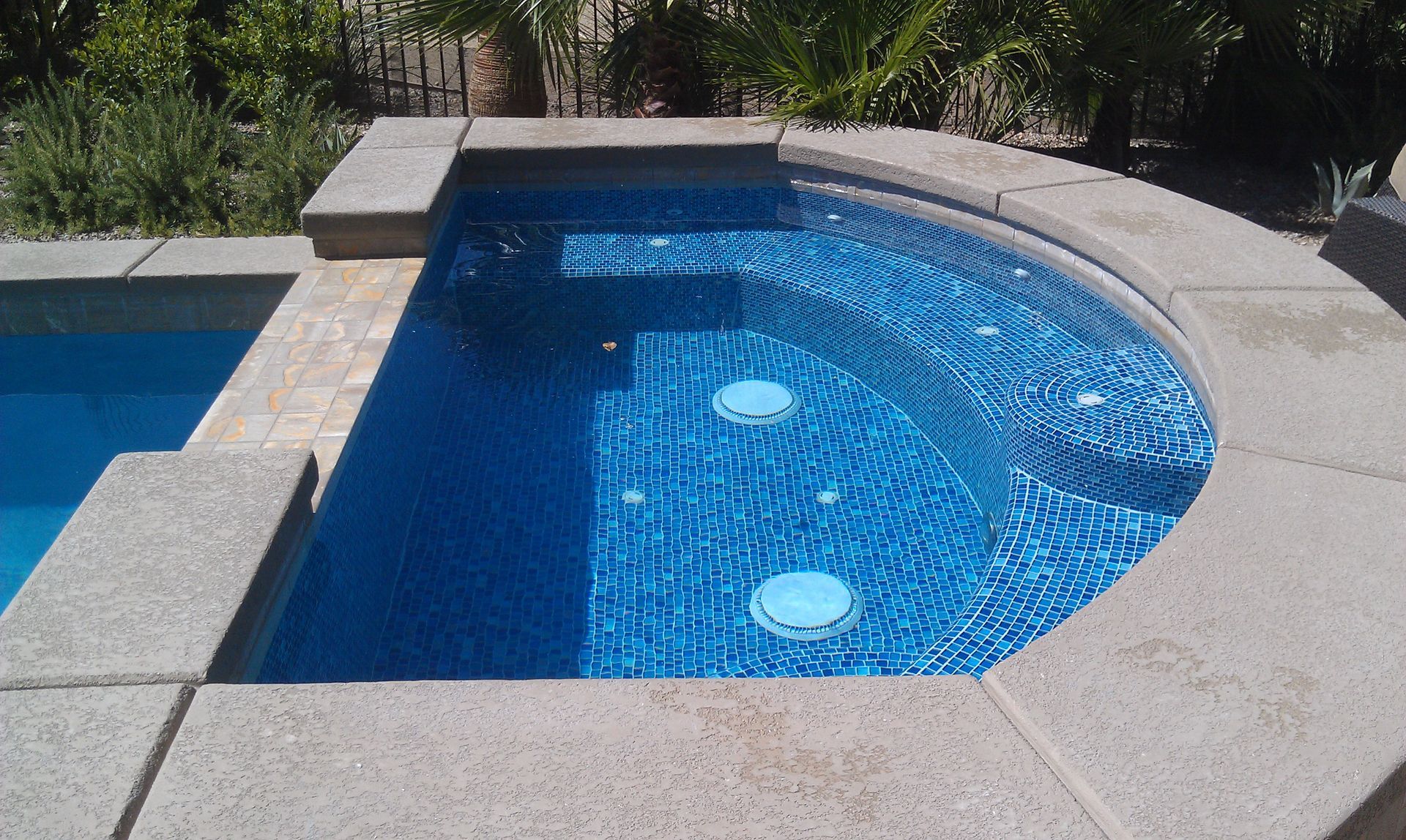 A swimming pool with a curved edge and blue tiles