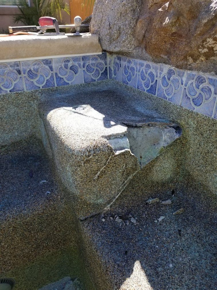 A swimming pool with a broken tile border and steps.