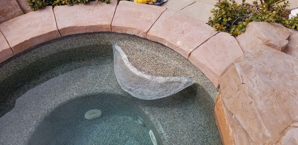 A close up of a hot tub surrounded by rocks and plants.