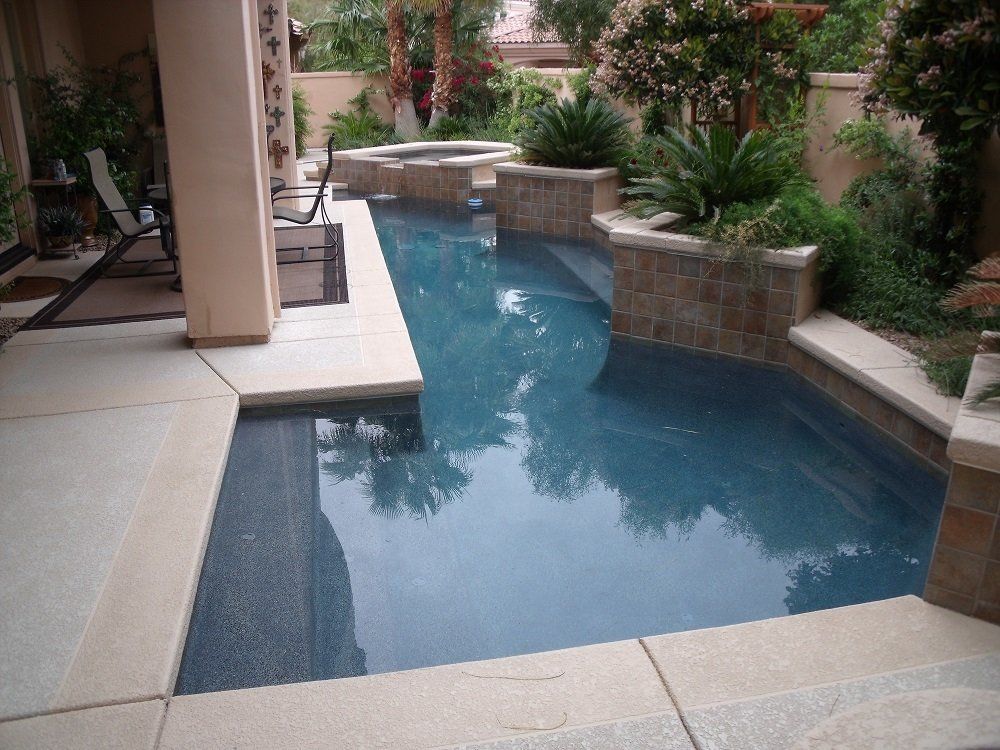 A large swimming pool with a hot tub in the backyard