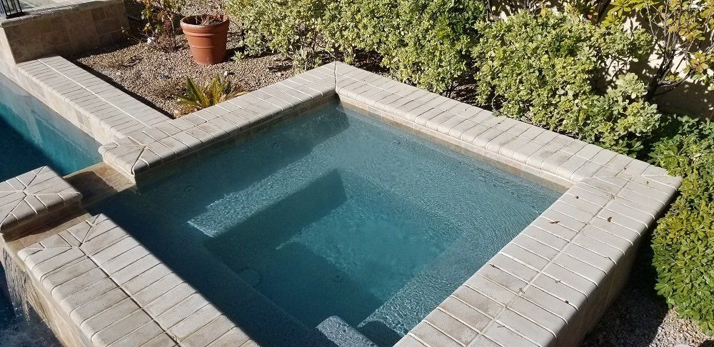 A swimming pool with a hot tub in the middle of it.