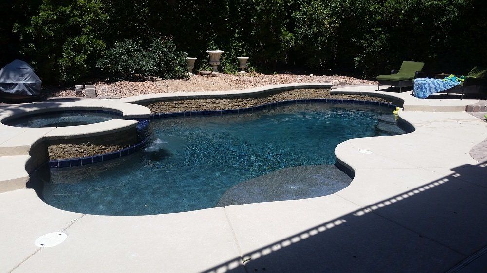 A large swimming pool with a hot tub in the backyard