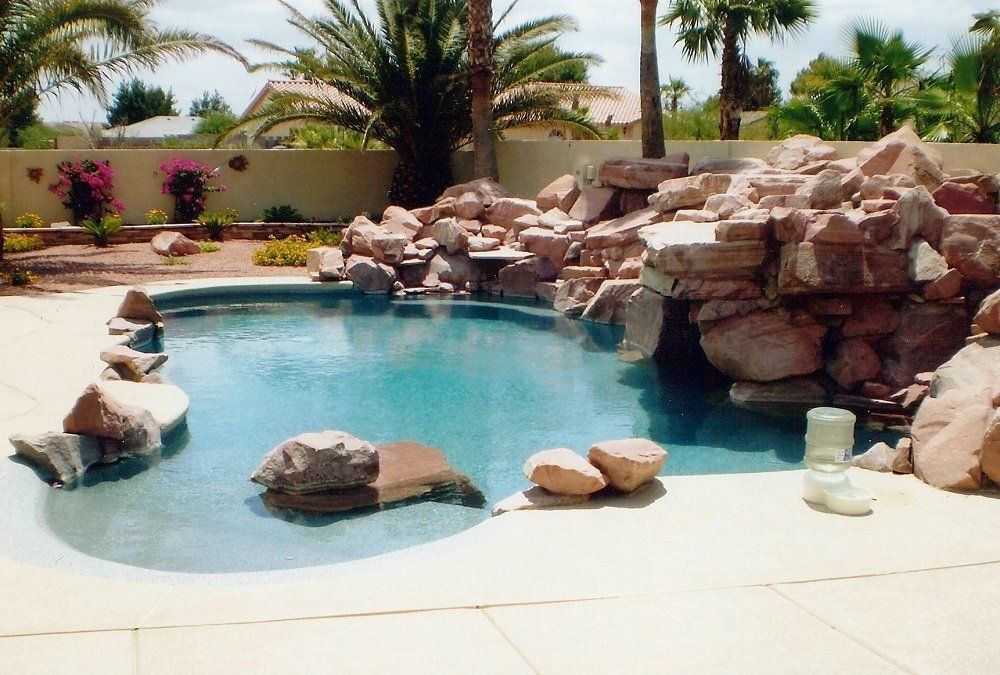 A large swimming pool surrounded by rocks and palm trees