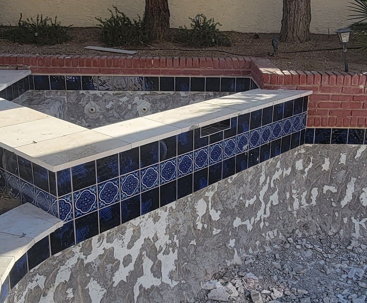 A swimming pool is being remodeled with blue and white tiles