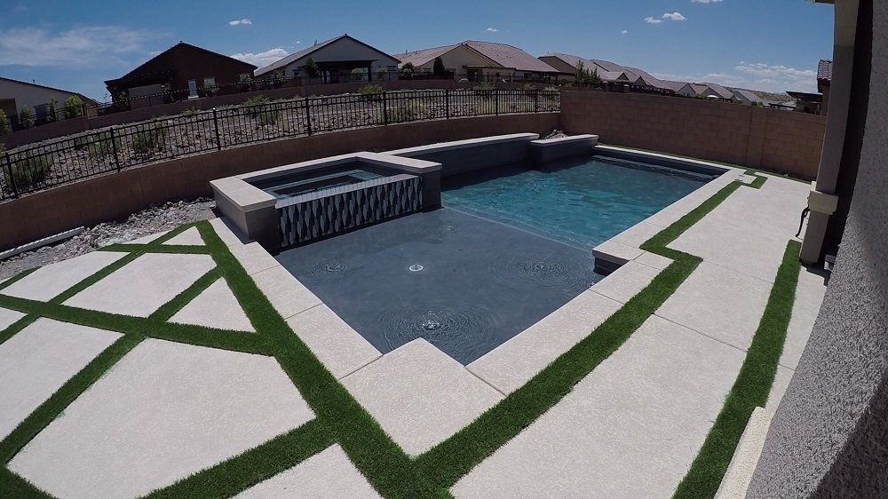 A large swimming pool with a hot tub in the backyard of a house.