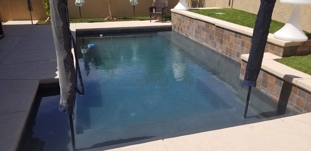 A large swimming pool is sitting on top of a concrete patio.