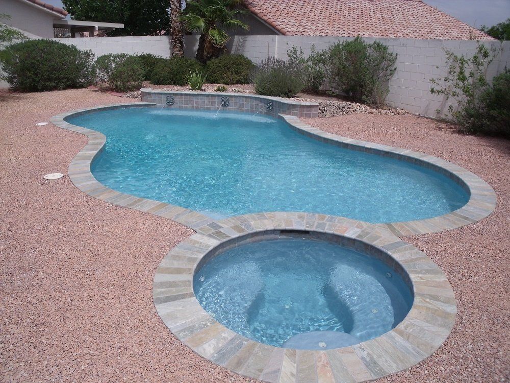 A swimming pool with a hot tub next to it