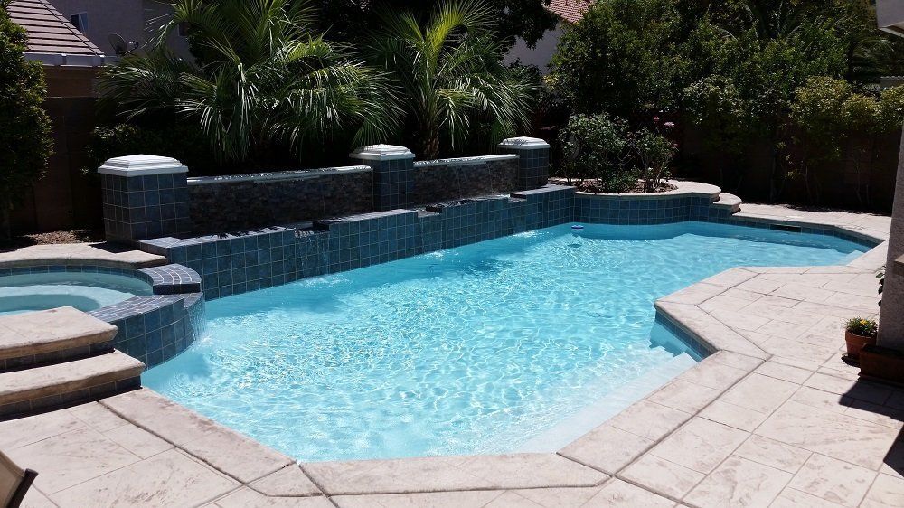 A large swimming pool with a hot tub in the backyard