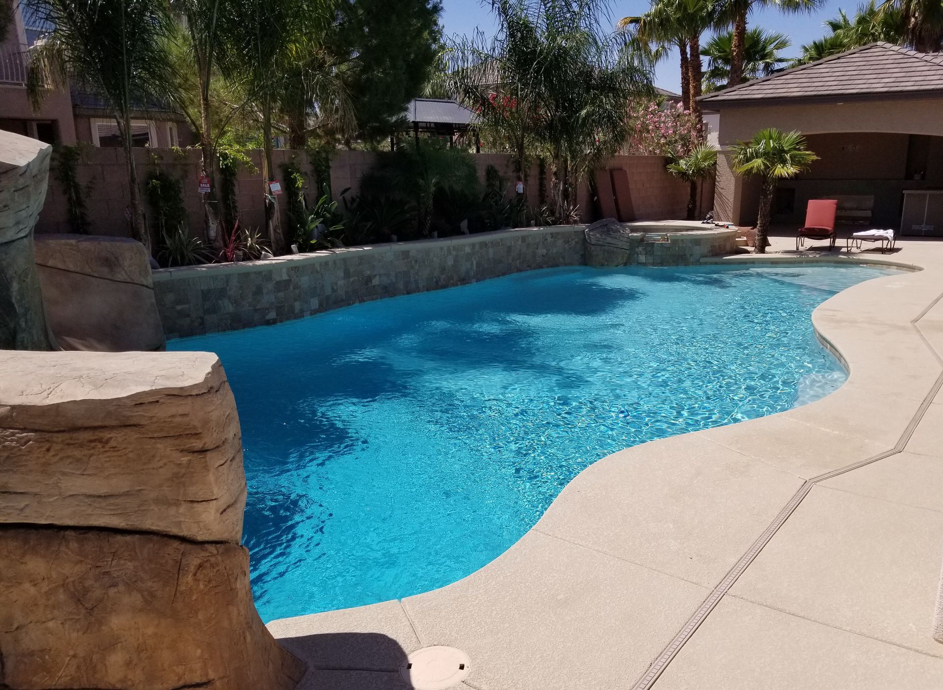 A large swimming pool surrounded by rocks and palm trees