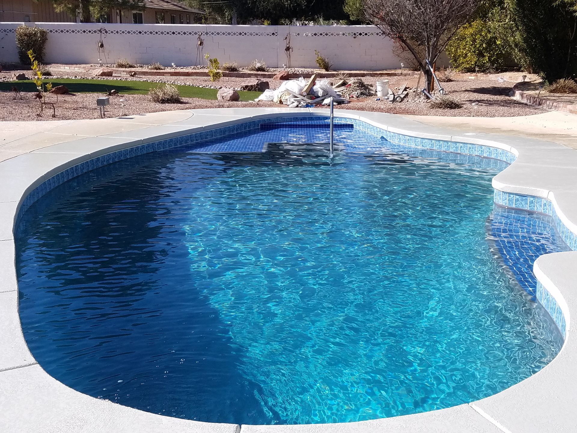 A large swimming pool with a white wall in the background