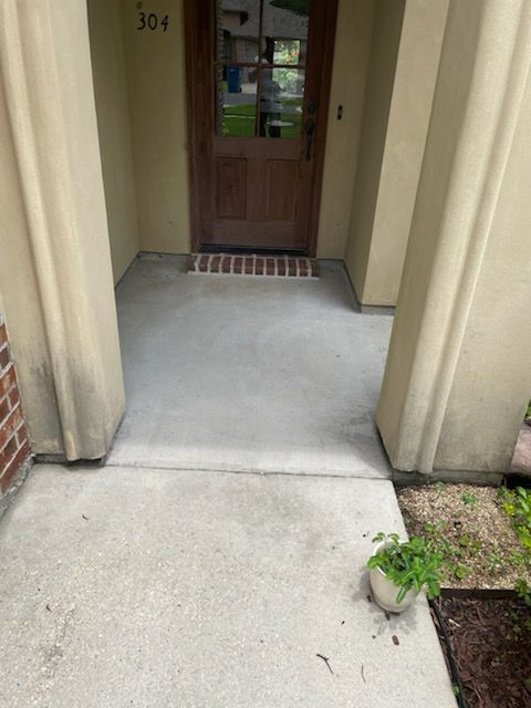 Concrete porch entrance with tan columns and a brown door. Number 304 above the door.