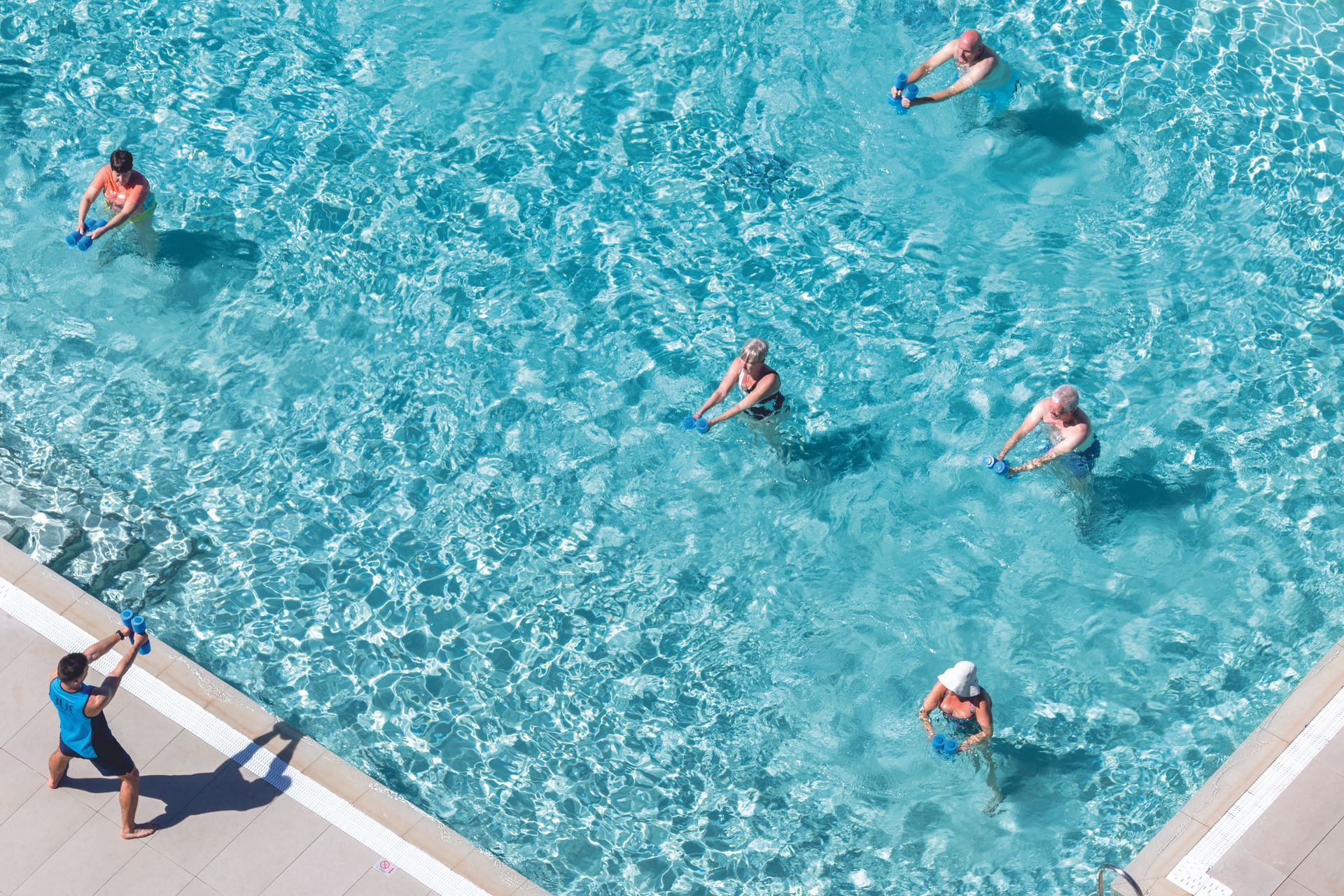 People doing water aerobics in a pool led by an instructor.