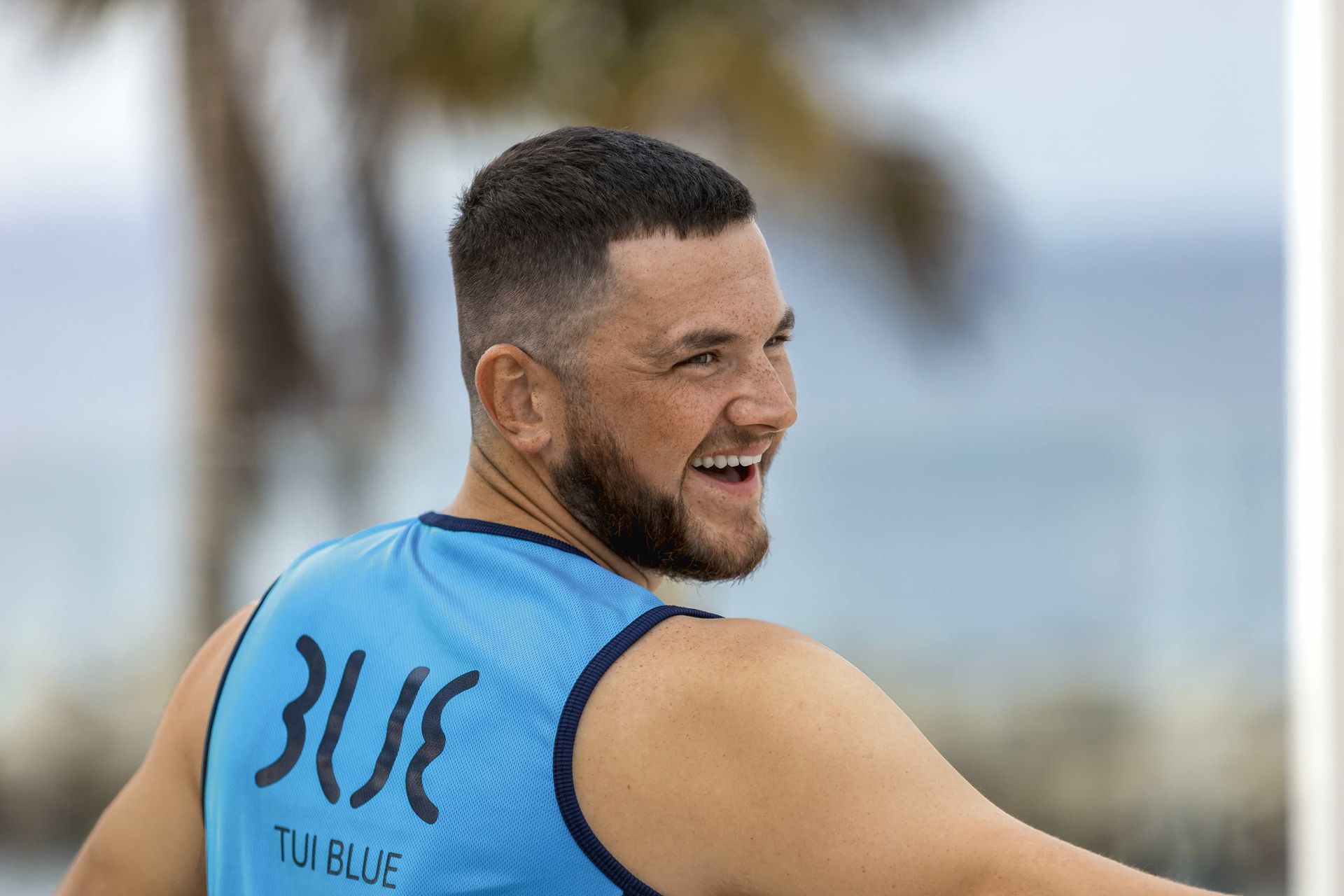 Woman in yellow dress dances on pier, blue sky, people, shops in background.