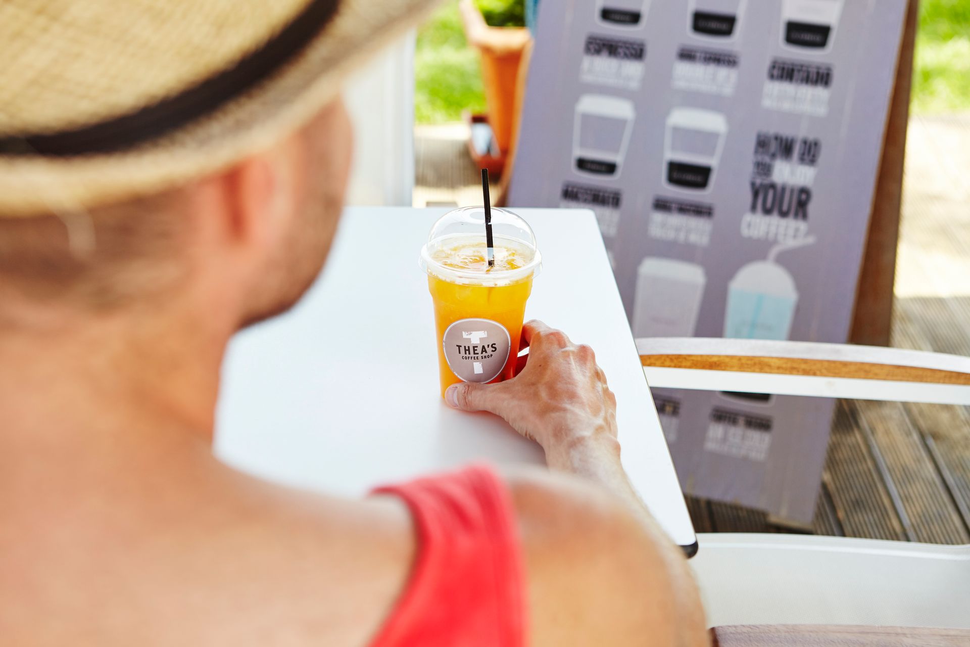 Two drinks with straws on a counter, fruit display, barista in background.