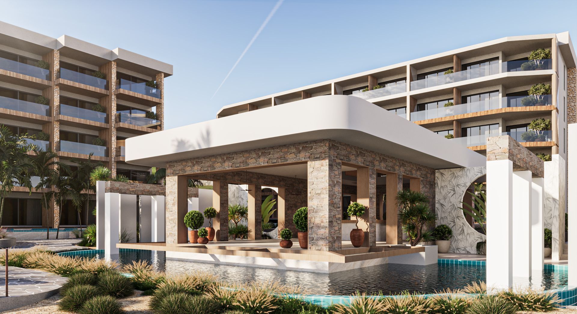 Hotel entrance with stone columns, turquoise water, and multiple-story buildings in background.