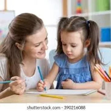 Tutor helping a young girl with her schoolwork at a table.