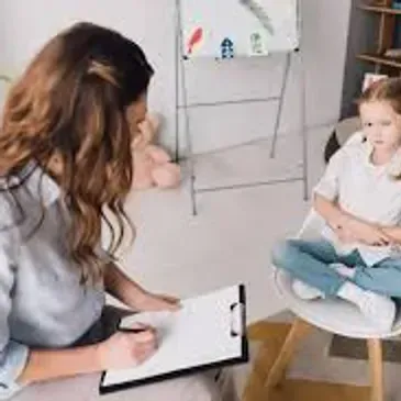 Female tutor engaging with a child while sitting on the floor.