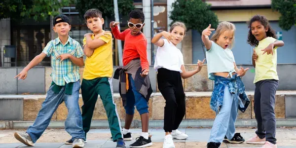 Group of diverse children dancing and holding hands outdoors.