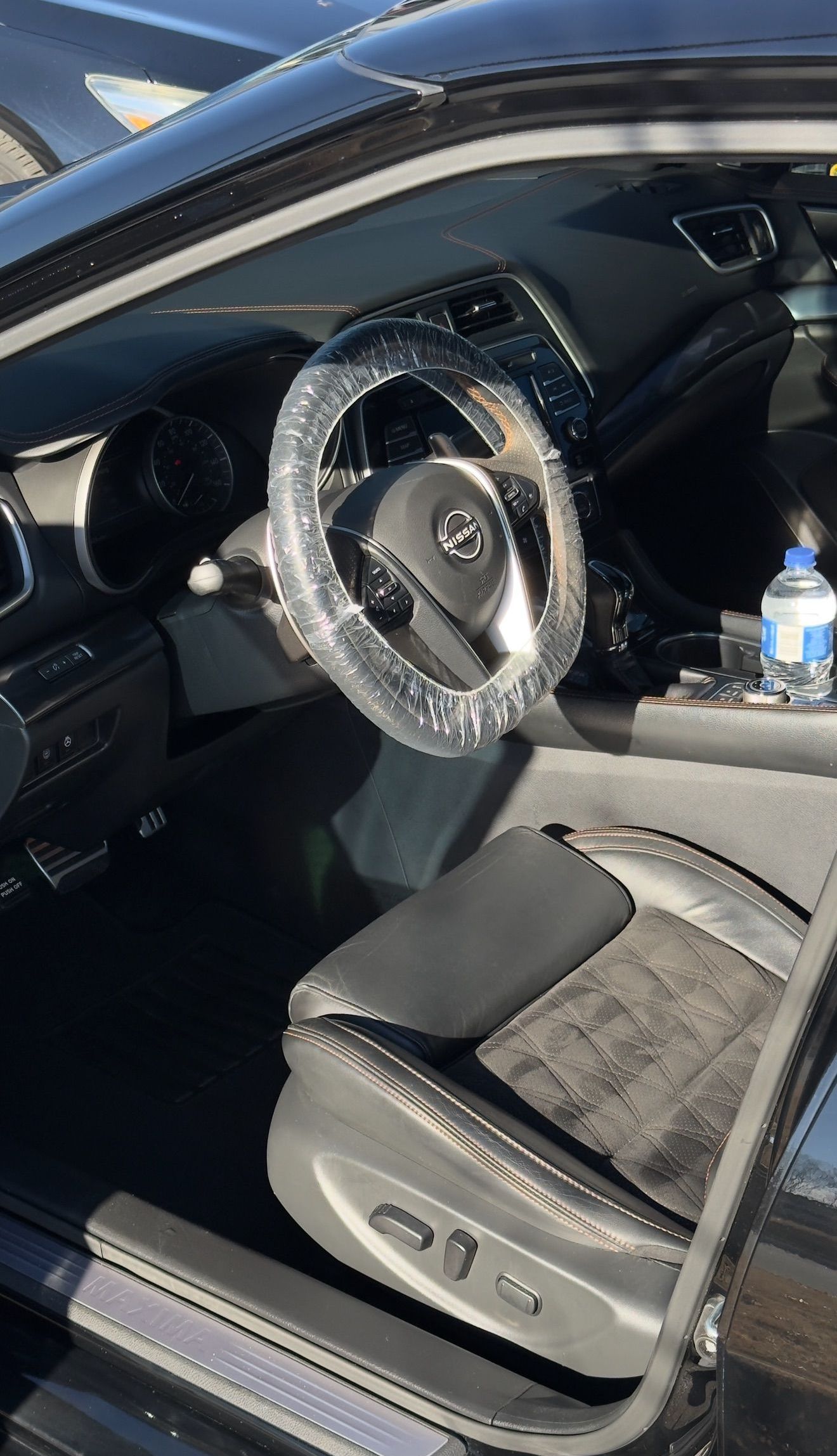 The inside of a car with a steering wheel covered in rhinestones.