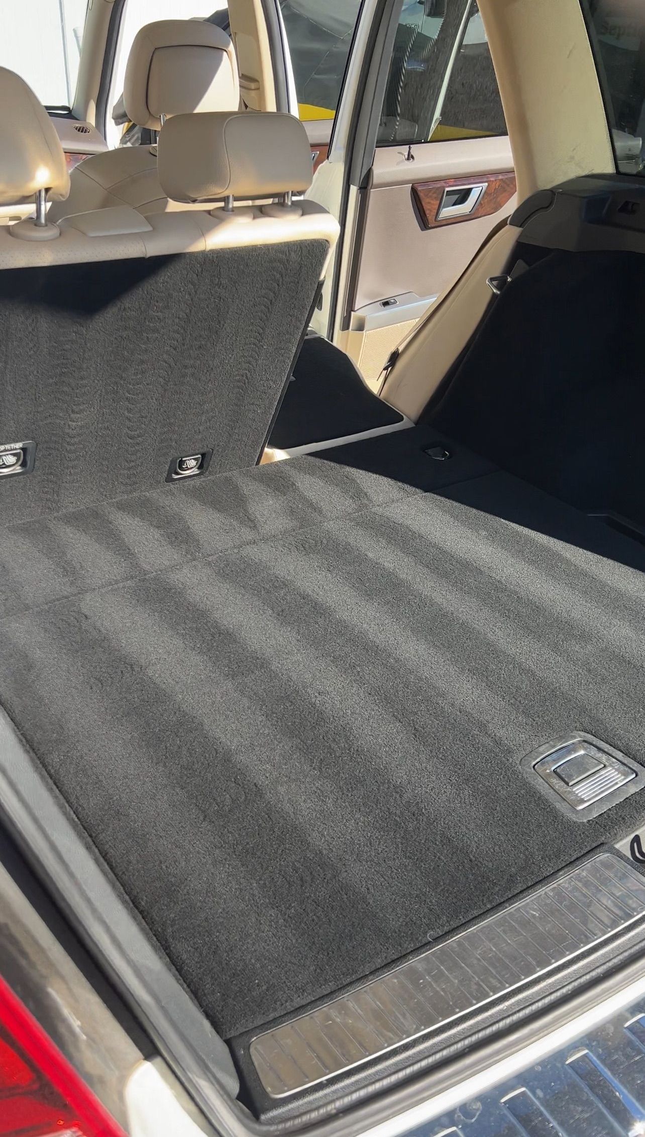 A close up of the trunk of a car with a carpeted floor.