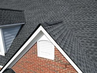 A brick house with a black roof and a white window