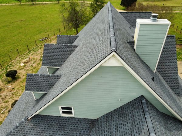 An aerial view of a house with a gray roof and a chimney.