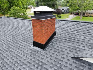 A brick chimney is sitting on top of a roof.