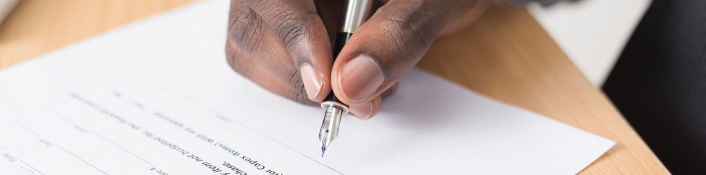 a person is writing on a piece of paper with a pen .