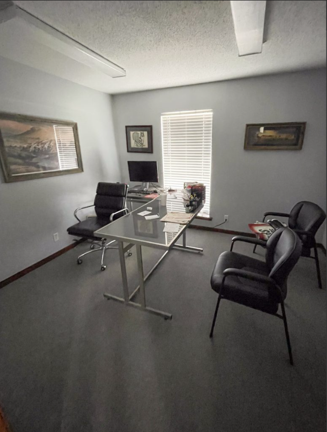 a room with a desk and chairs and a window
