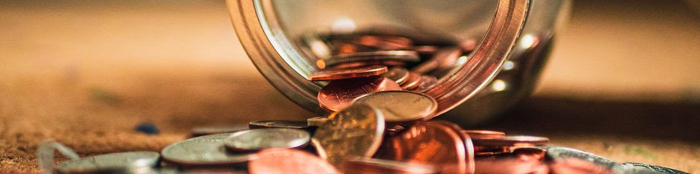 a person is putting coins into a glass jar .