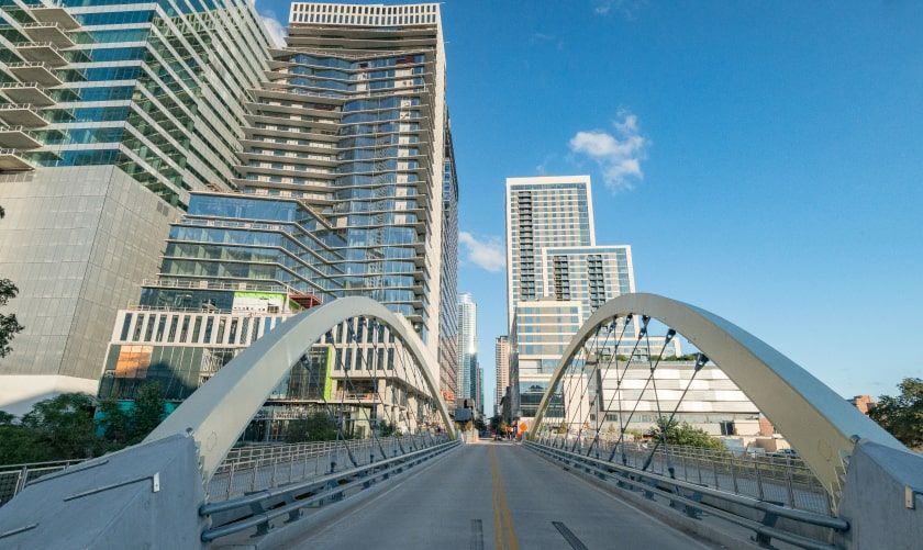 a bridge over a city street with tall buildings in the background .