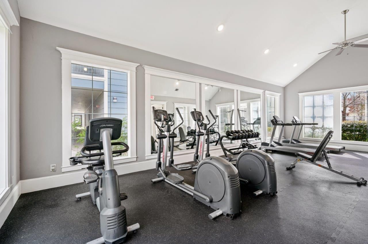 A gym with a lot of exercise equipment and a lot of windows.