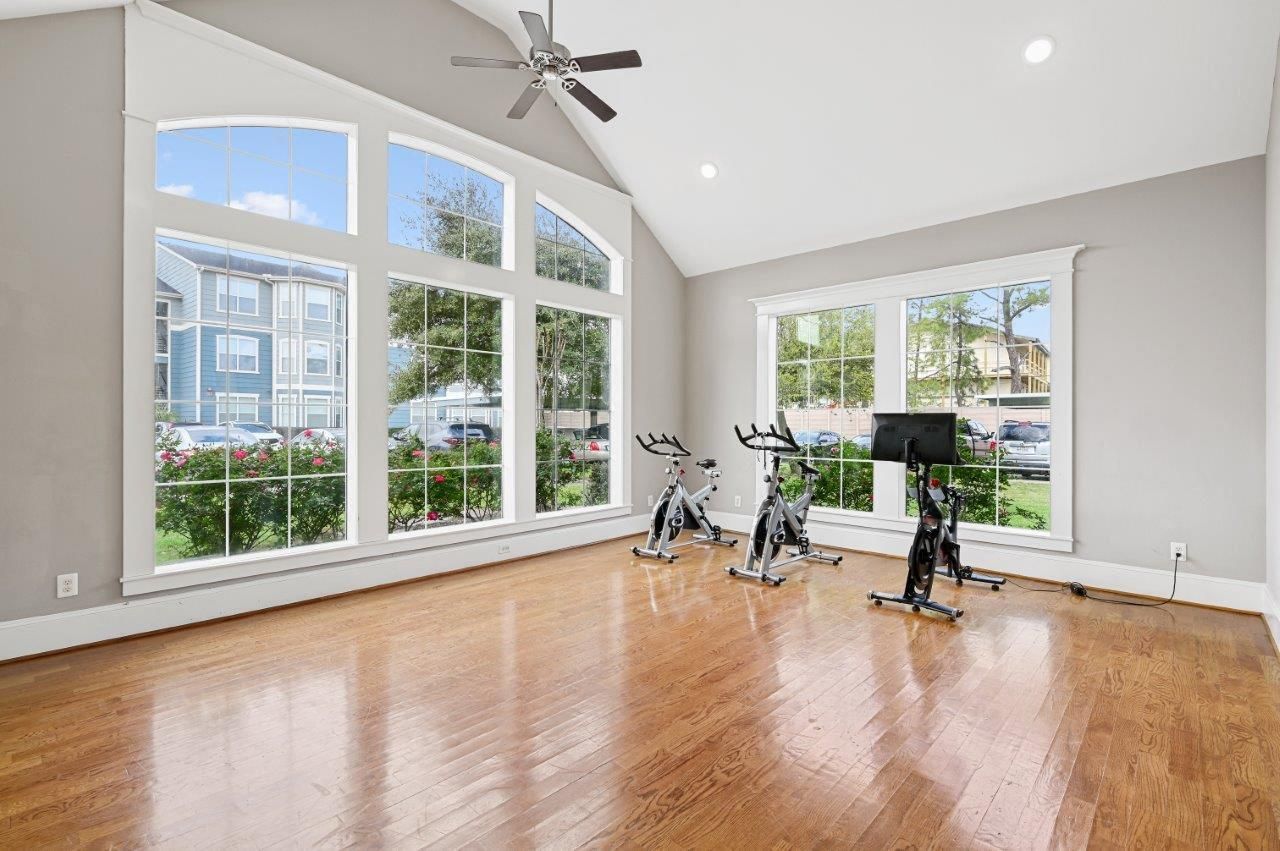 There are two exercise bikes in the room with a lot of windows.