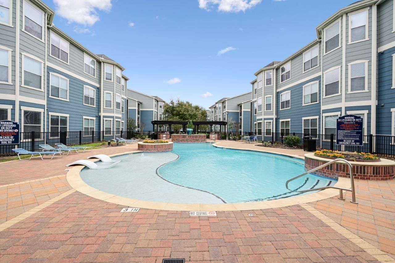 A large swimming pool in the middle of a apartment complex.