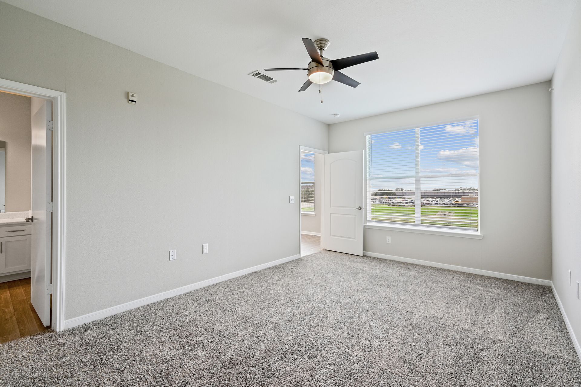 An empty bedroom with a ceiling fan and a window.