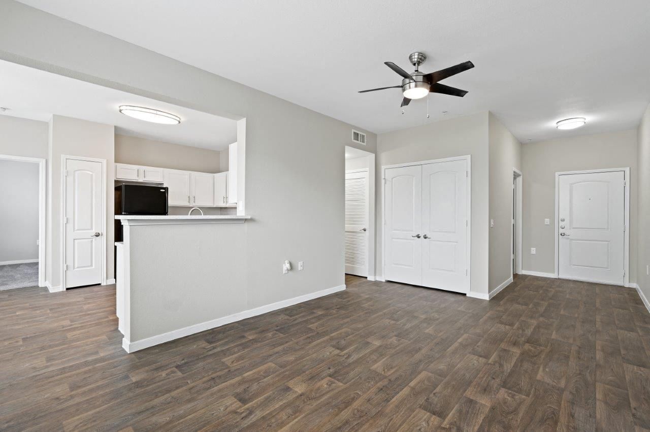 An empty living room with hardwood floors and a ceiling fan.