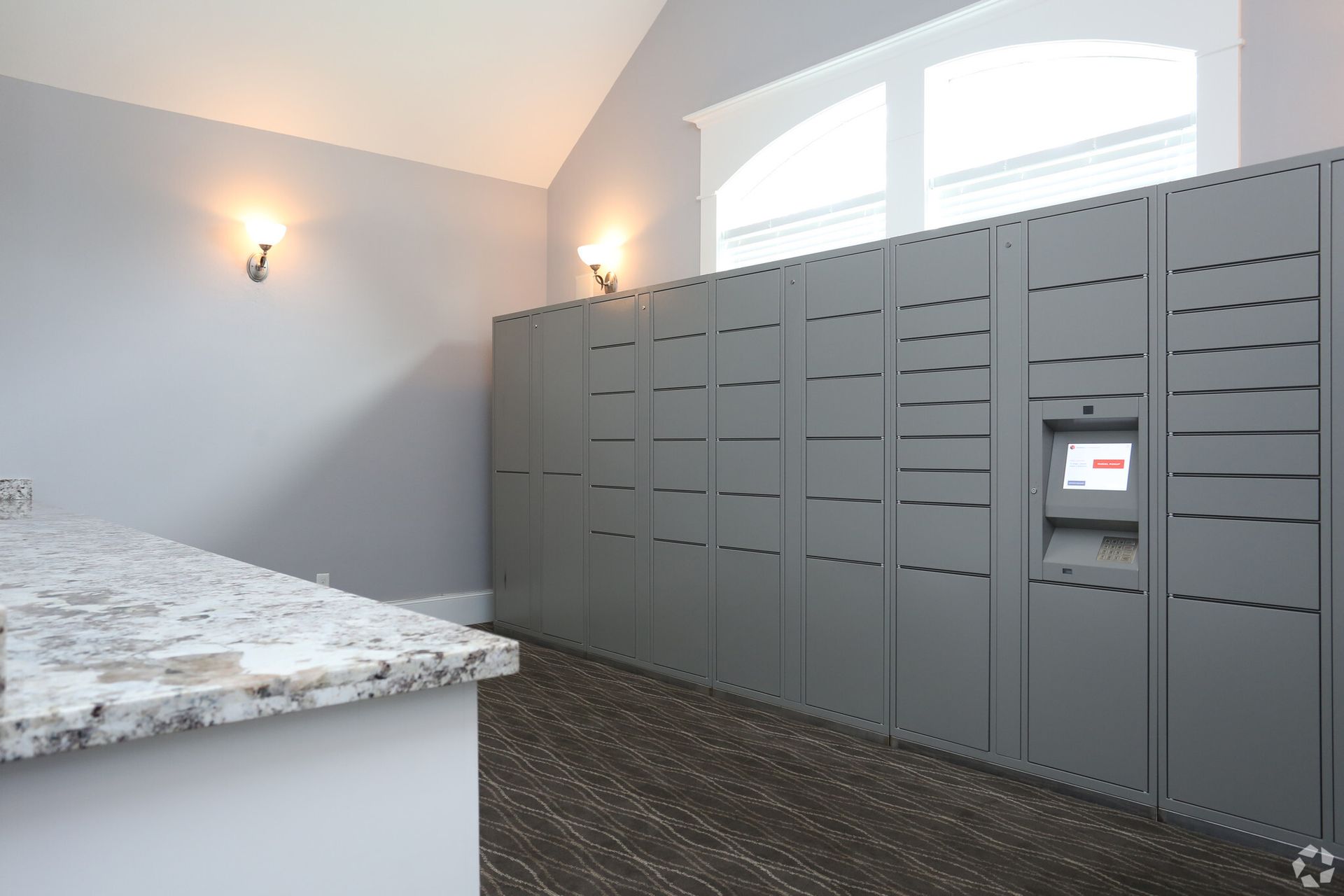 A room with a lot of lockers and a counter top.