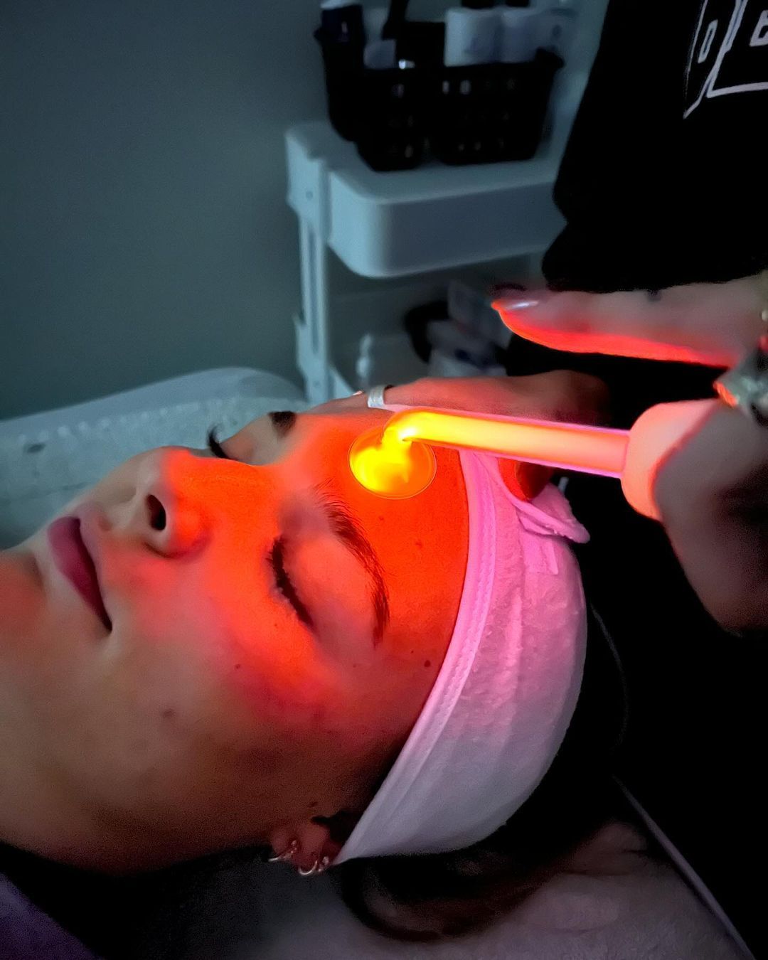 Facial treatment with a red-glowing wand on a person's face.