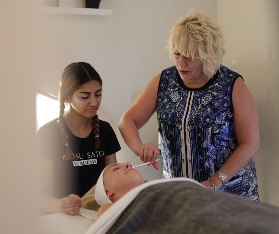 Woman administering treatment on another while a student observes in a clinic.