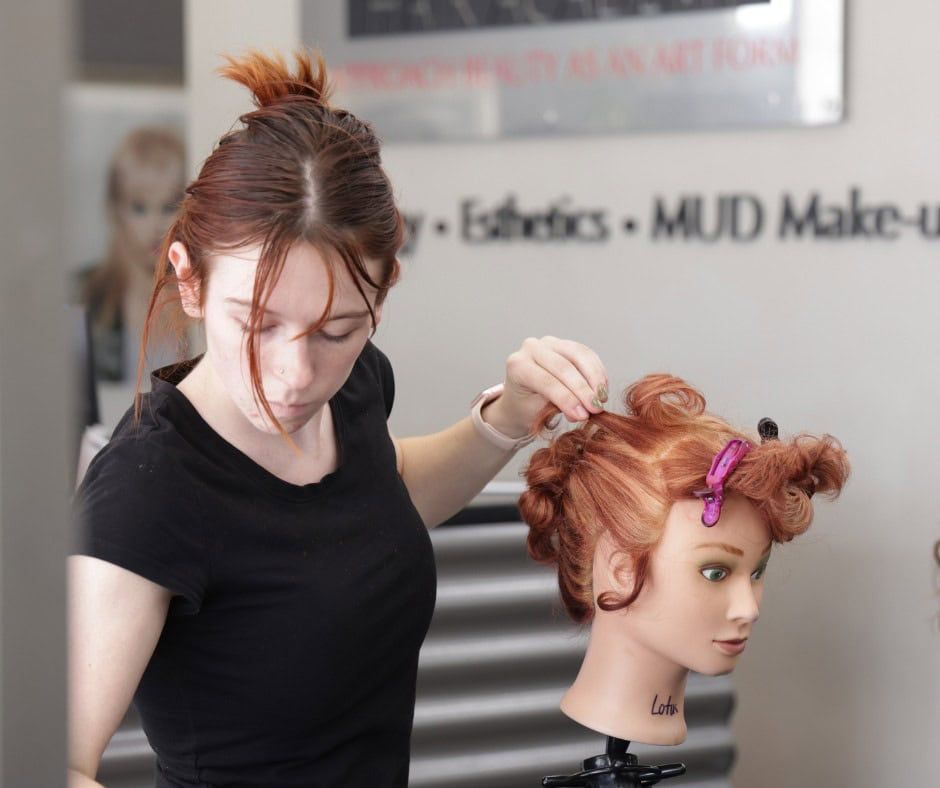 Hair stylist styling mannequin head with red hair.