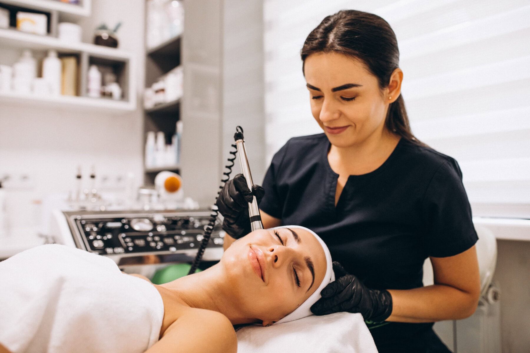Woman receiving facial treatment from a cosmetologist in a spa.